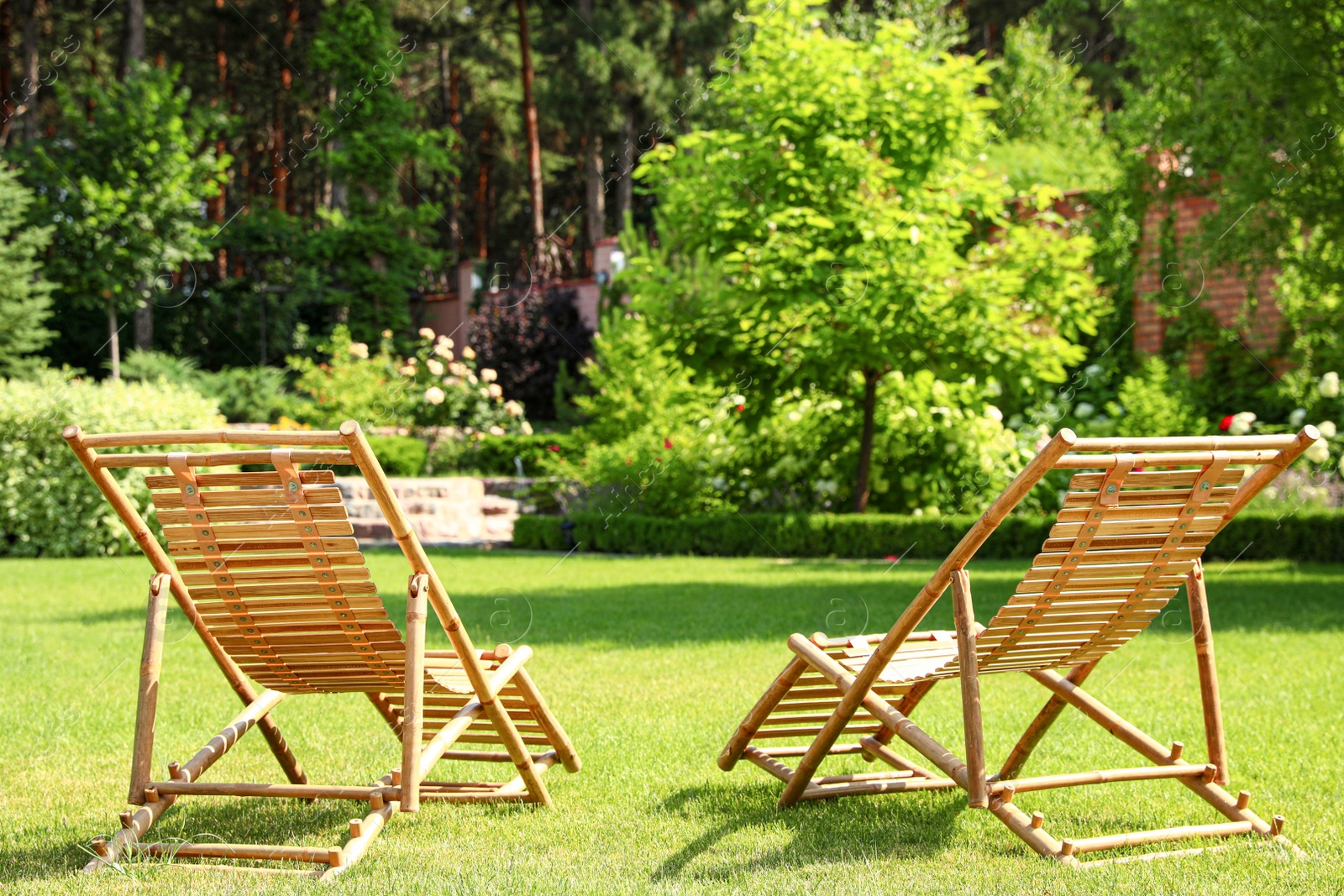 Photo of Wooden deck chairs in beautiful garden on sunny day