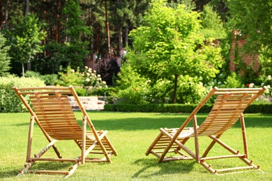 Wooden deck chairs in beautiful garden on sunny day