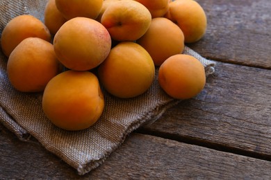 Photo of Delicious ripe apricots with napkin on wooden table, closeup