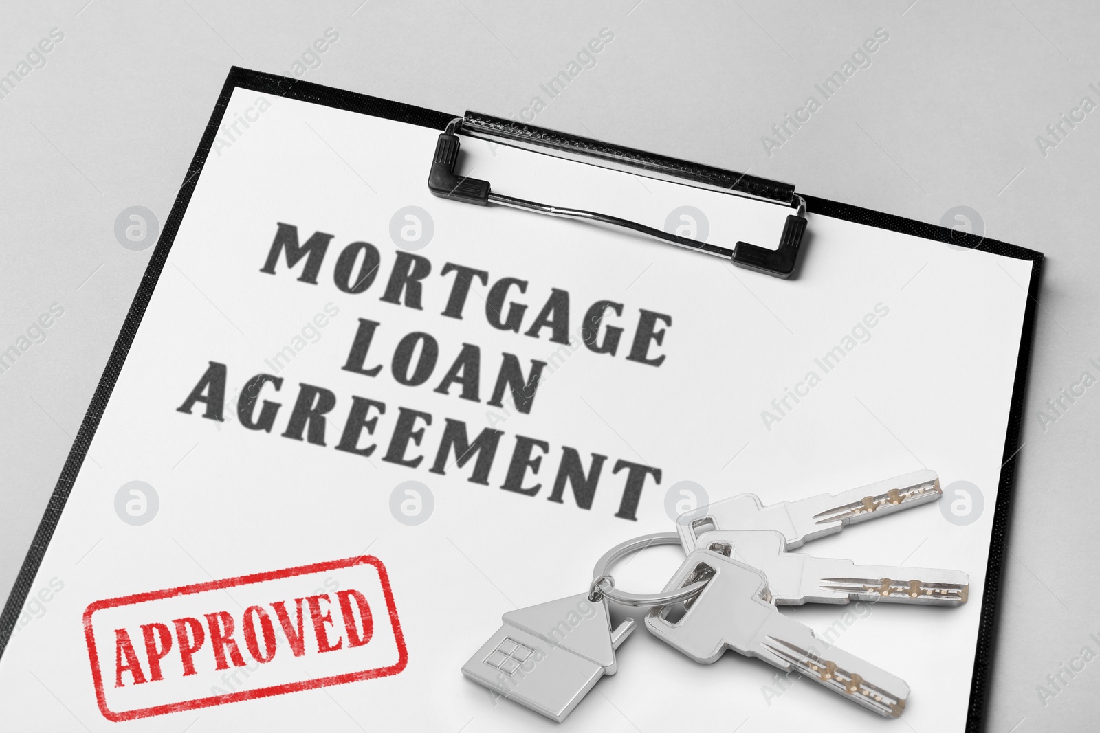 Image of Mortgage loan agreement with Approved stamp and house keys on table, closeup