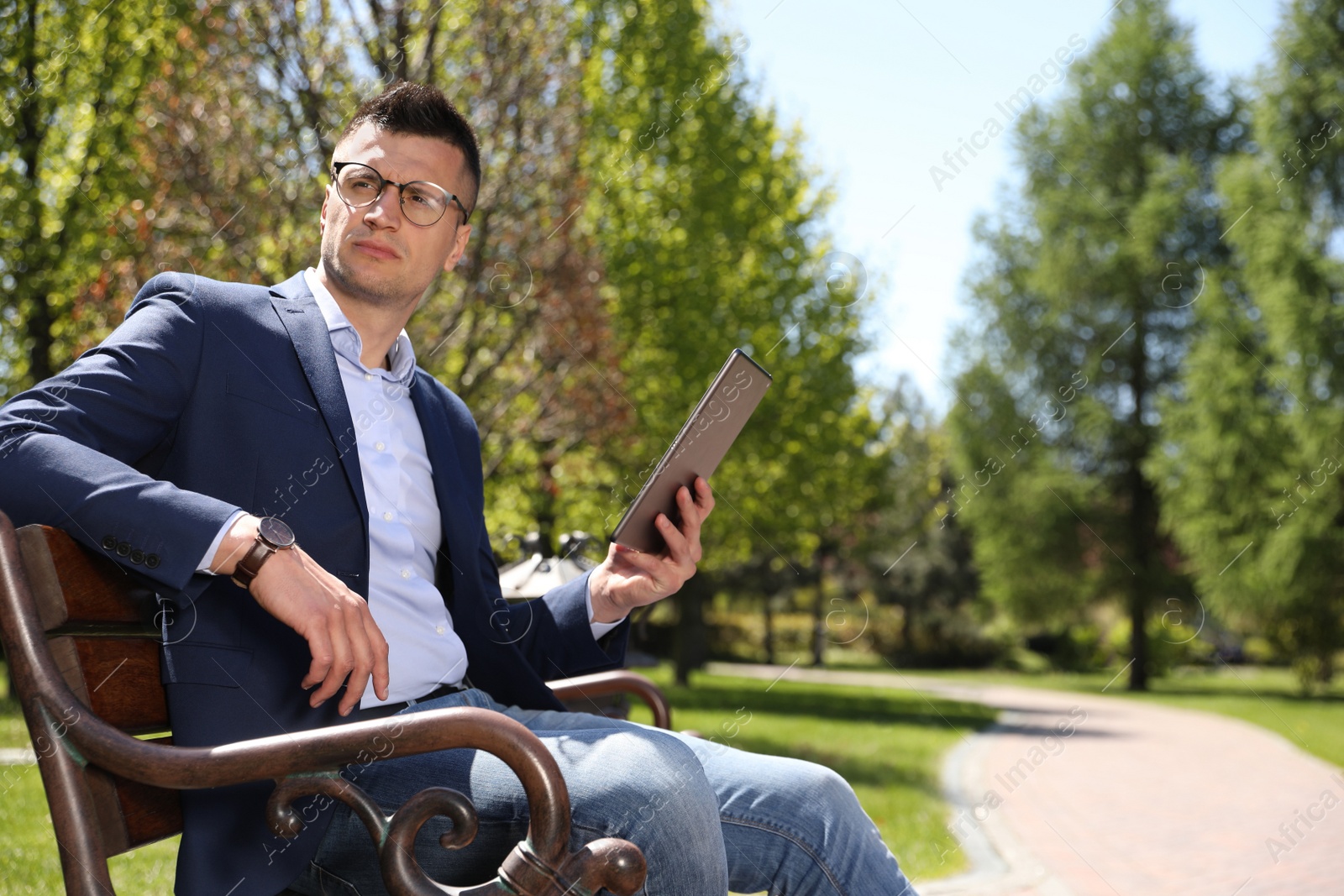 Photo of Man working with tablet on bench in park