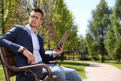 Man working with tablet on bench in park