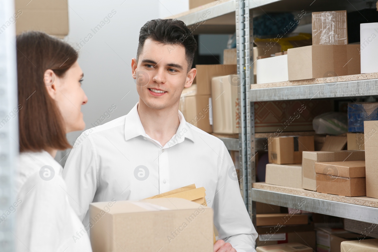 Photo of Post office workers with parcels near rack indoors