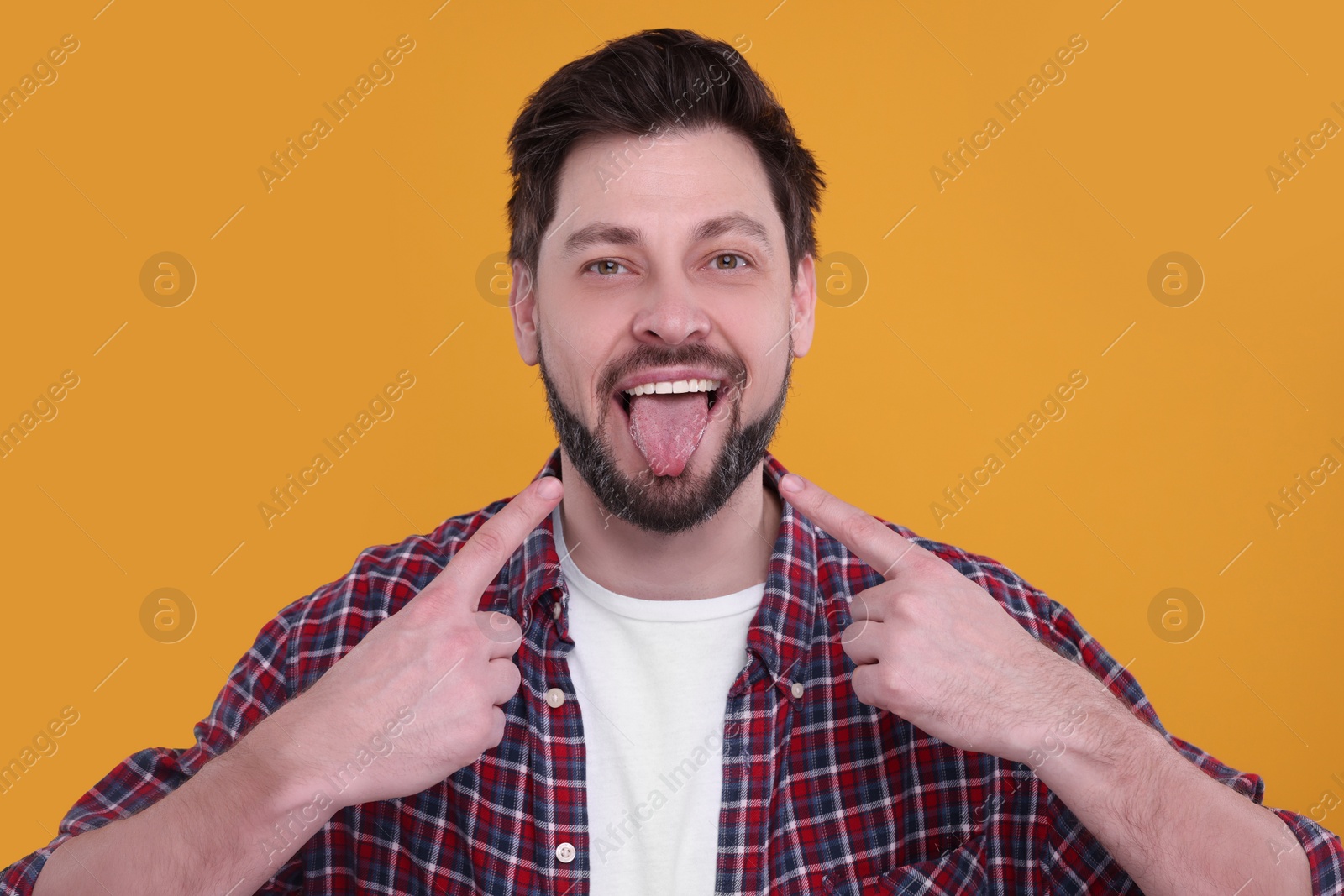 Photo of Happy man showing his tongue on orange background