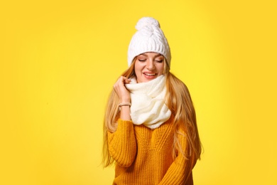 Photo of Portrait of emotional young woman in stylish hat, sweater and scarf on color background. Winter atmosphere