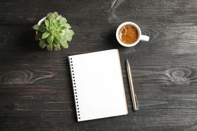 Photo of Notebook, coffee and plant on dark wooden background