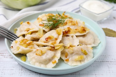 Photo of Cooked dumplings (varenyky) with tasty filling, fried onions and dill on wooden table, closeup
