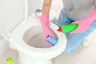 Photo of Woman cleaning toilet bowl in bathroom