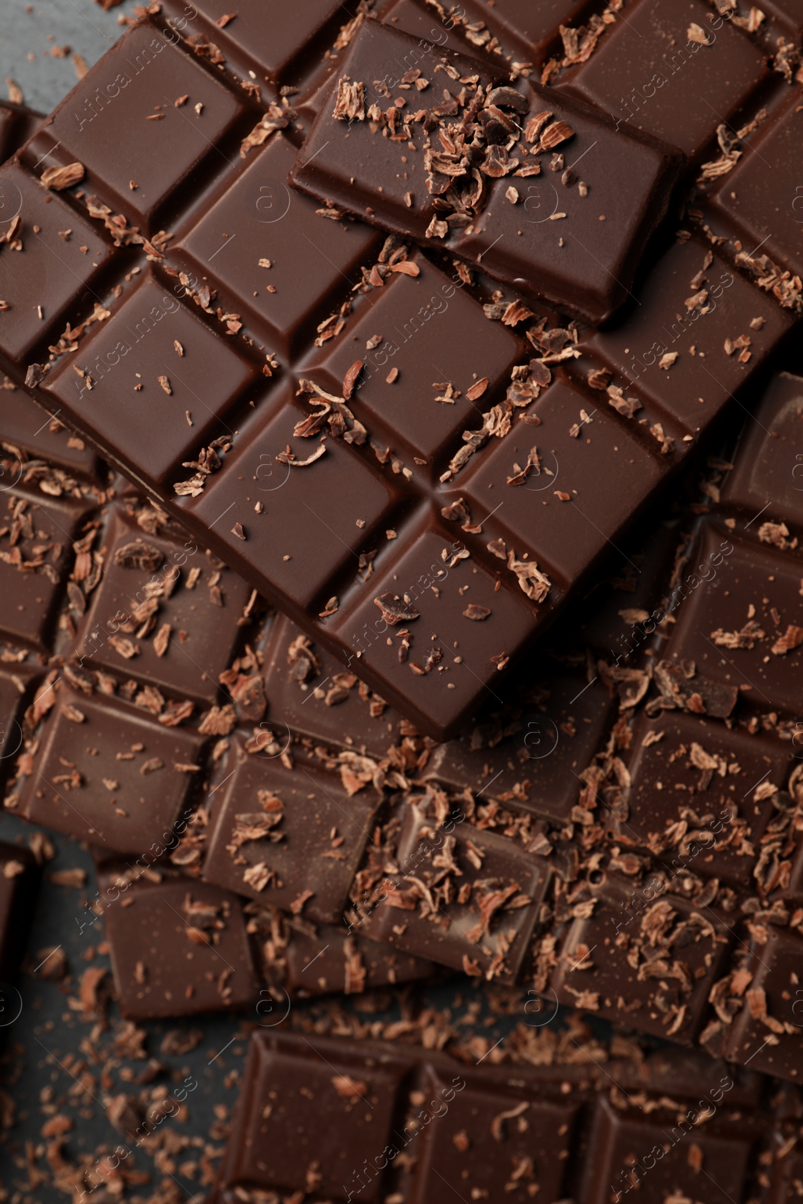 Photo of Pieces and shavings of tasty chocolate bars on grey table, flat lay