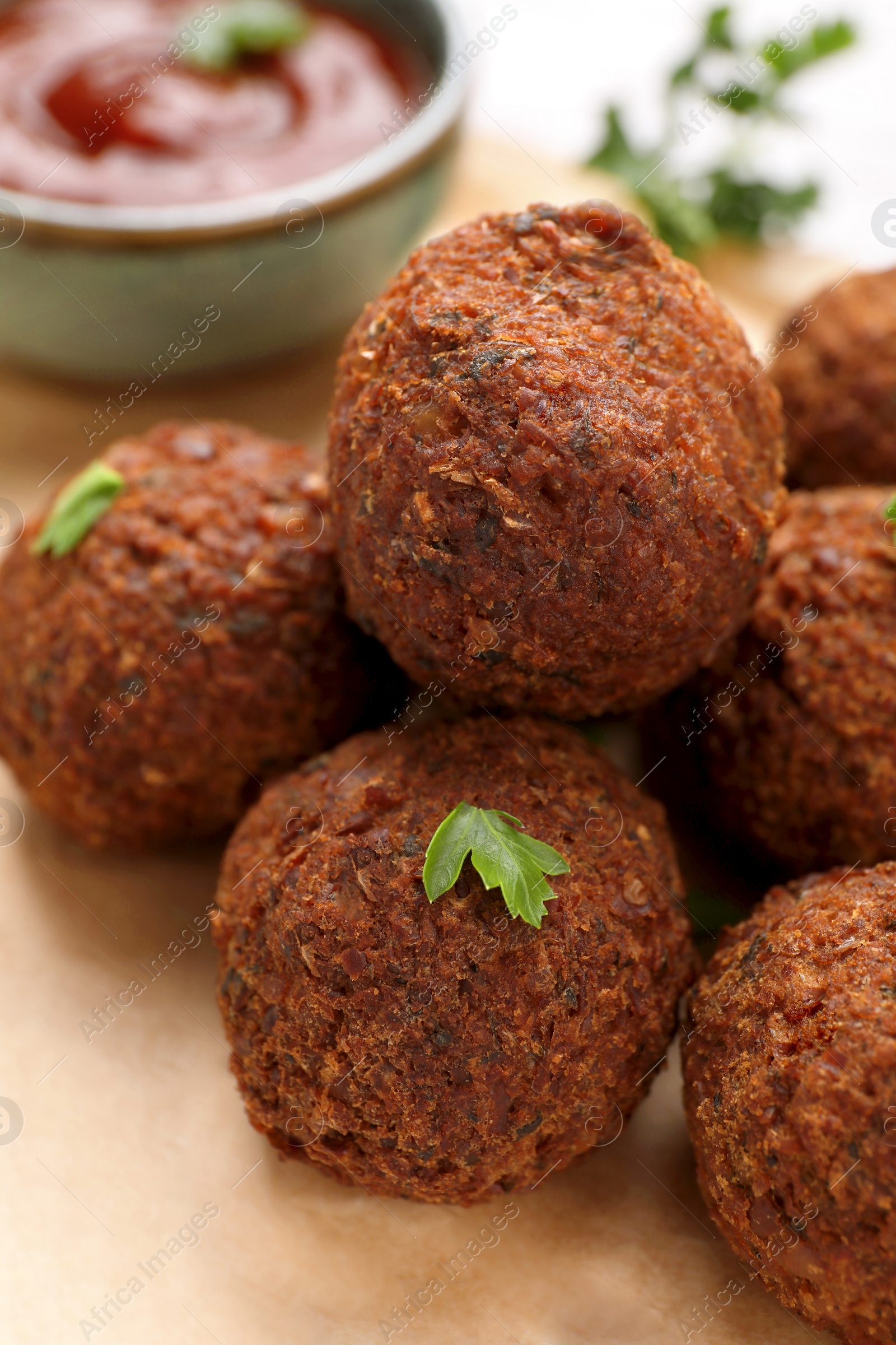 Photo of Delicious falafel balls and parsley on parchment paper, closeup. Vegan meat products