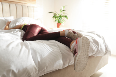Photo of Lazy young woman sleeping on bed instead of morning training, focus on legs