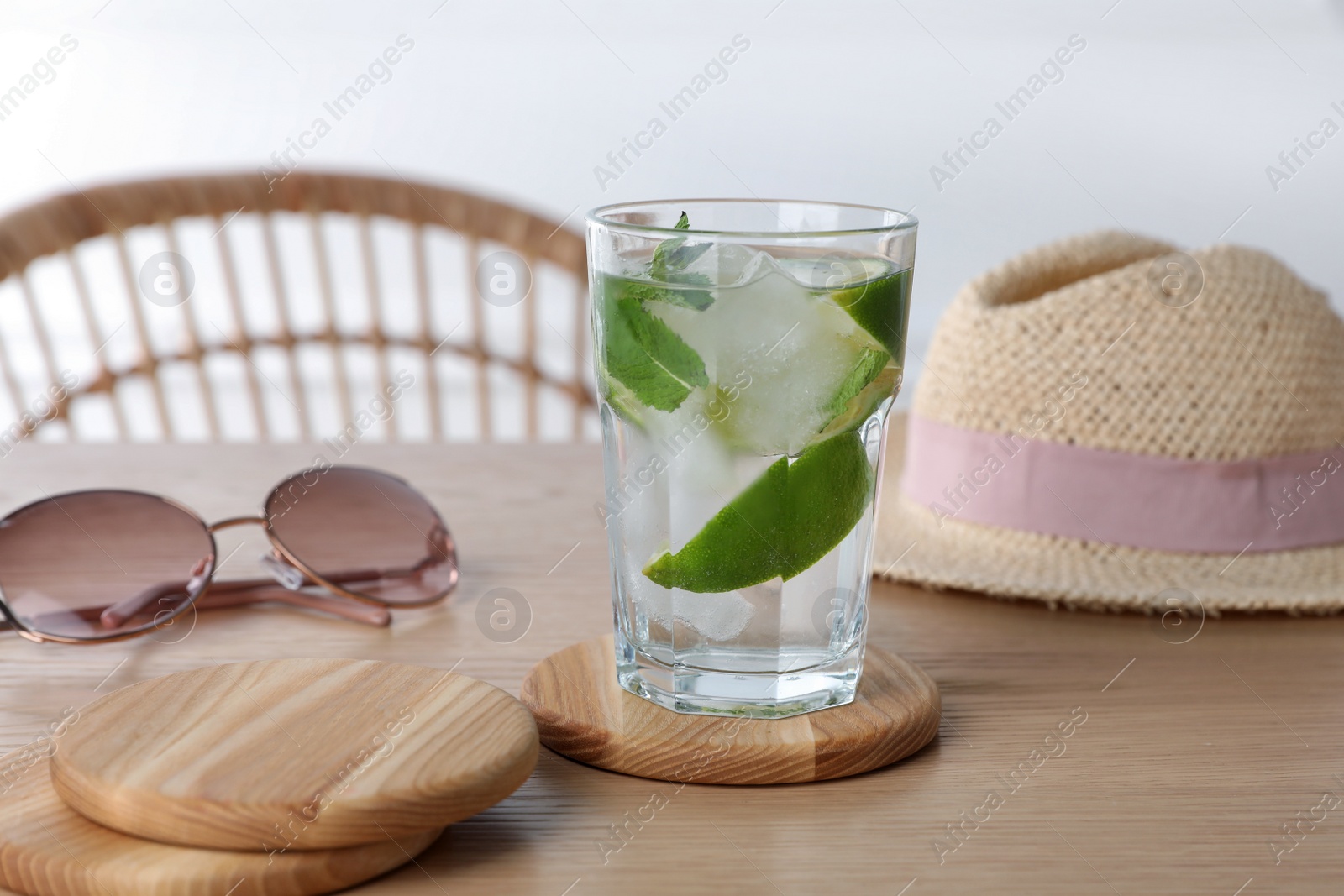 Photo of Glass of lemonade and stylish cup coasters on wooden table