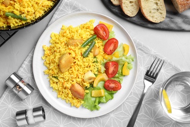 Delicious pilaf with chicken meat served on light grey table, flat lay