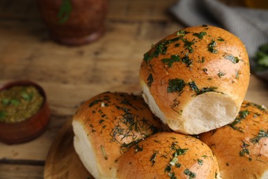 Photo of Traditional pampushka buns with garlic and herbs on wooden board, closeup