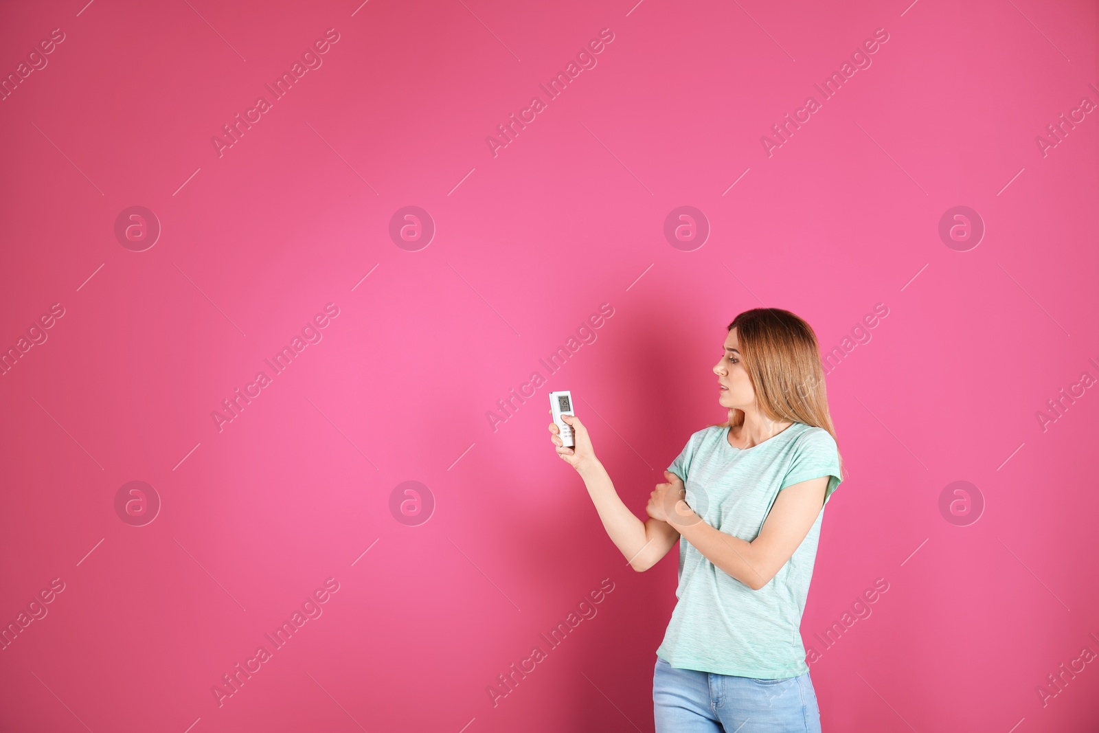 Photo of Woman with air conditioner remote on color background