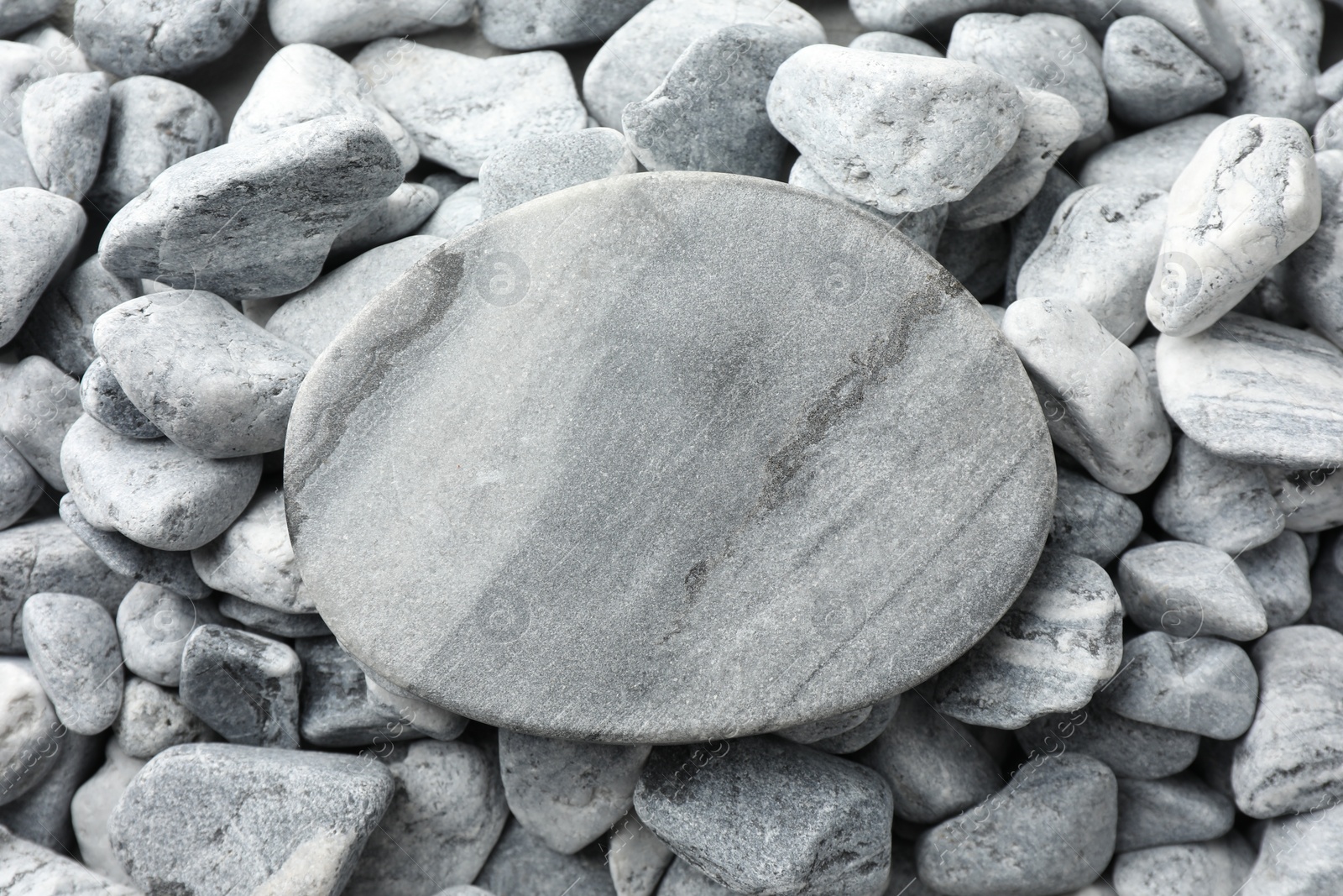 Photo of Presentation for product. Stone podium on grey pebbles, top view