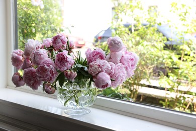 Beautiful pink peonies in vase on window sill, space for text. Interior design