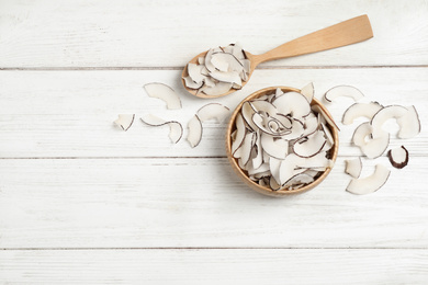 Photo of Tasty coconut chips on white wooden table, flat lay. Space for text