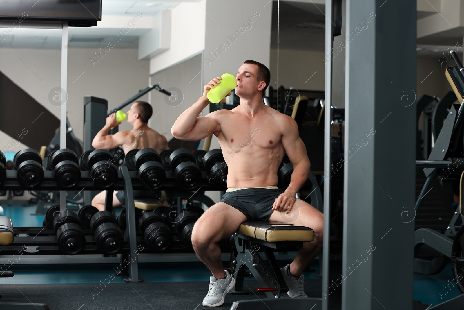Photo of Athletic young man drinking protein shake in gym