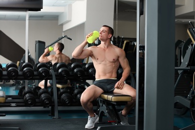 Athletic young man drinking protein shake in gym