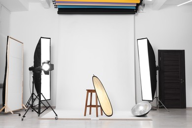 Photo of Stool with light reflector, professional lighting equipment and white background in photo studio