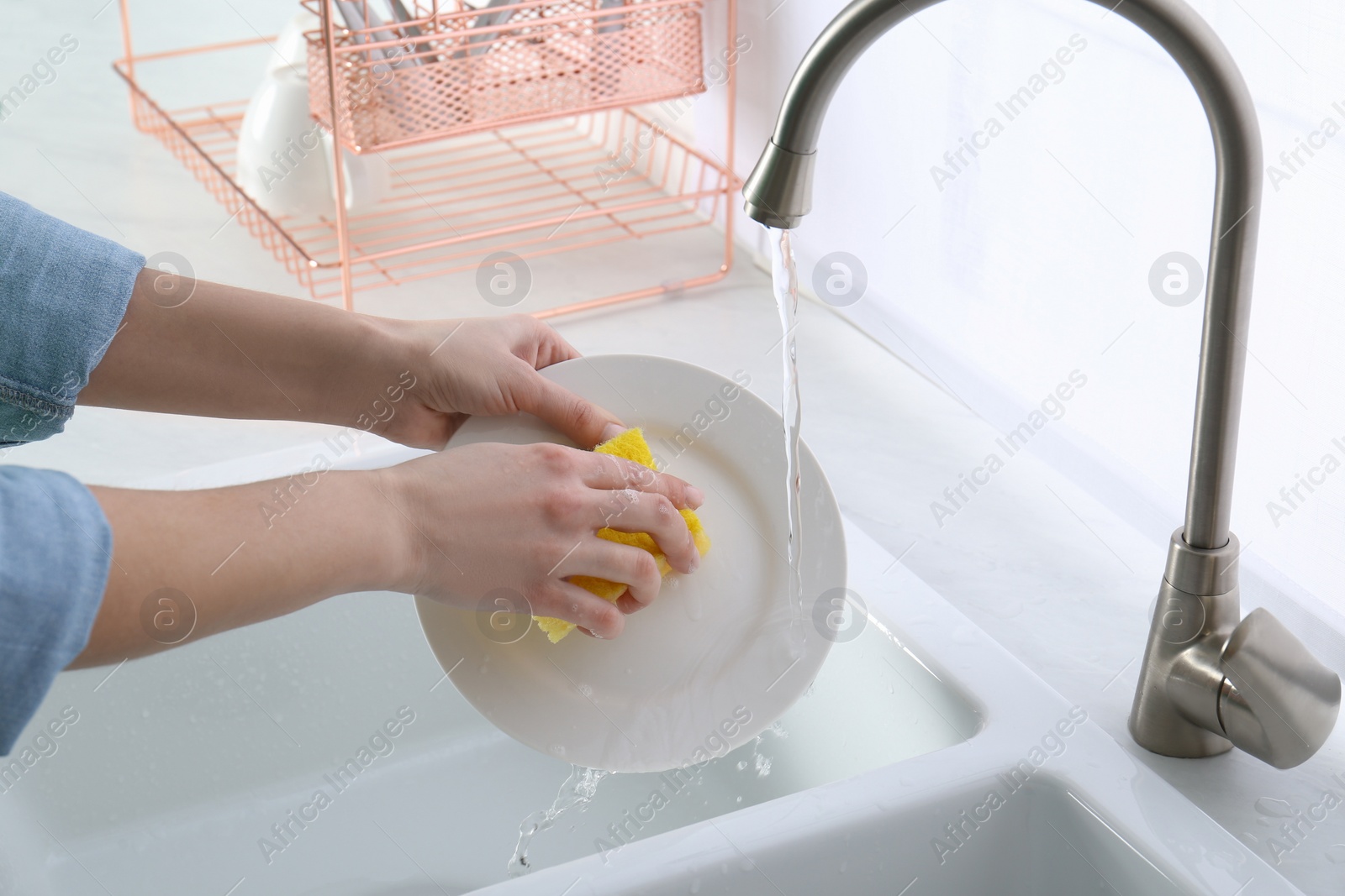 Photo of Woman washing plate in modern kitchen, closeup