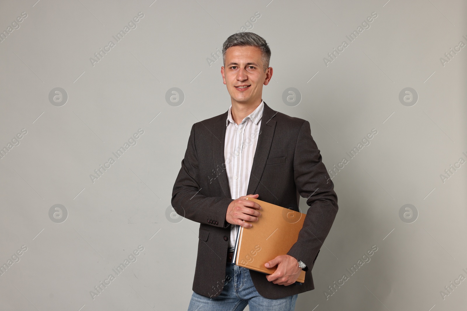 Photo of Happy teacher with notebooks on grey background