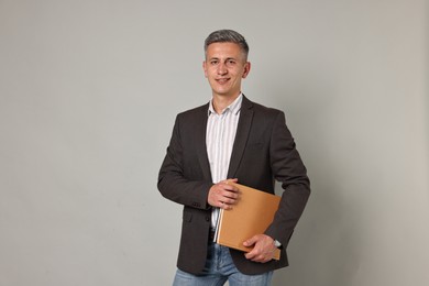 Photo of Happy teacher with notebooks on grey background