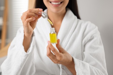 Young woman with serum in her hands indoors, closeup