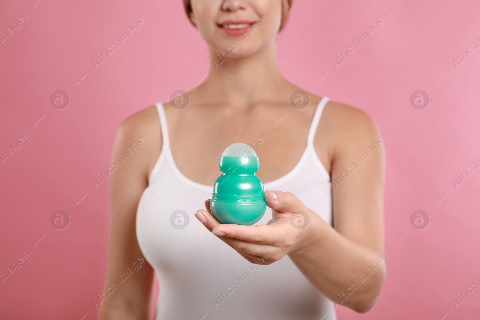 Photo of Young woman holding deodorant on pink background, closeup