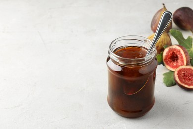 Jar of tasty sweet jam and fresh figs on light table, space for text