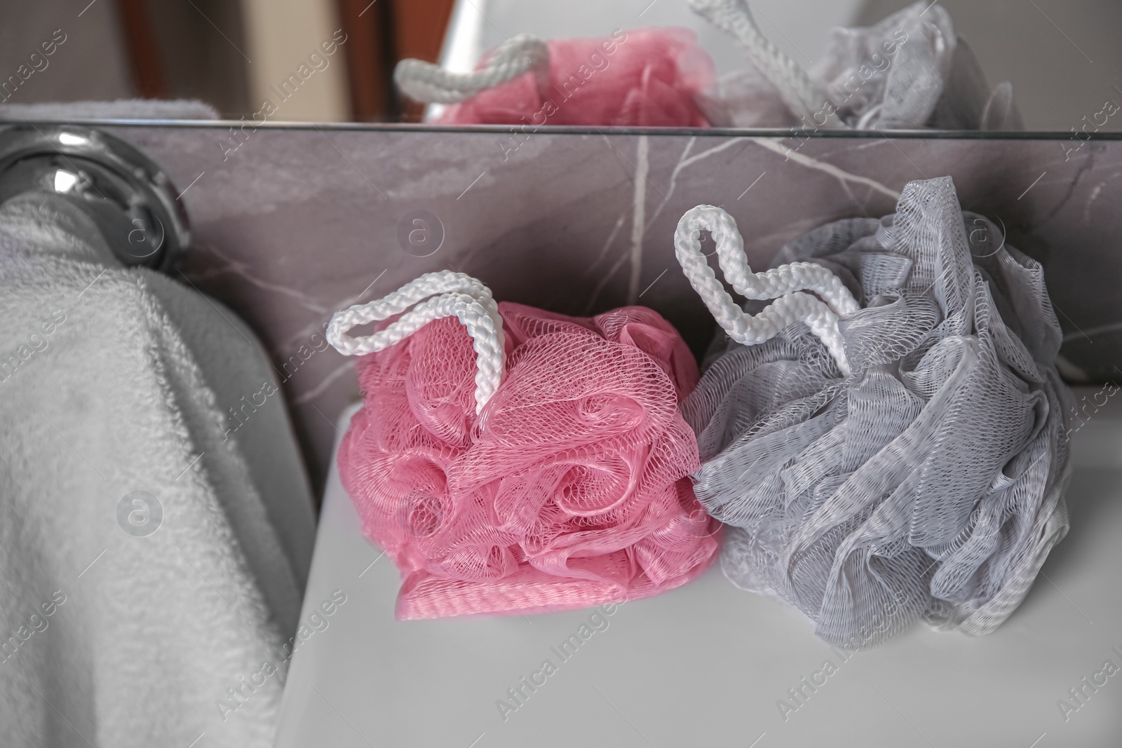 Photo of Colorful shower puffs on washbasin in bathroom