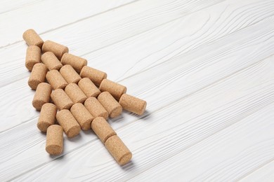 Photo of Christmas tree made of wine corks on white wooden table. Space for text