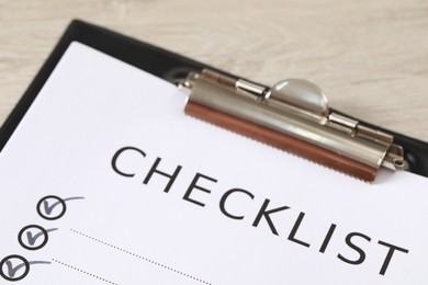 Clipboard with inscription Checklist on wooden table, closeup