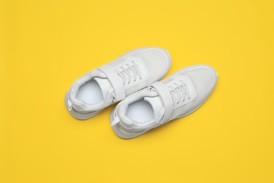 Photo of Pair of comfortable sports shoes on yellow background, flat lay