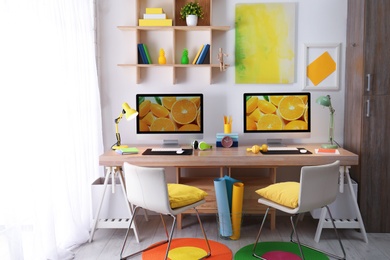 Modern workplace with large desk and computers in room. Stylish interior