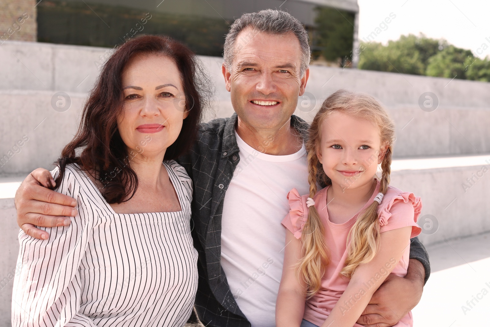 Photo of Couple of pensioners with granddaughter sitting outdoors