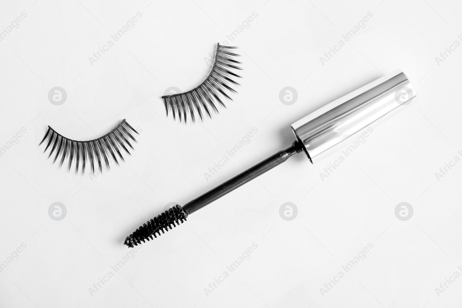 Photo of Mascara brush and false eyelashes on grey background, flat lay