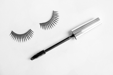 Mascara brush and false eyelashes on grey background, flat lay