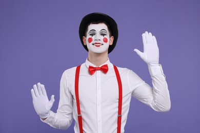 Photo of Funny mime artist in hat posing on purple background