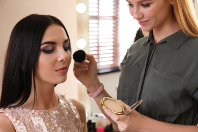 Professional makeup artist working with beautiful woman in salon