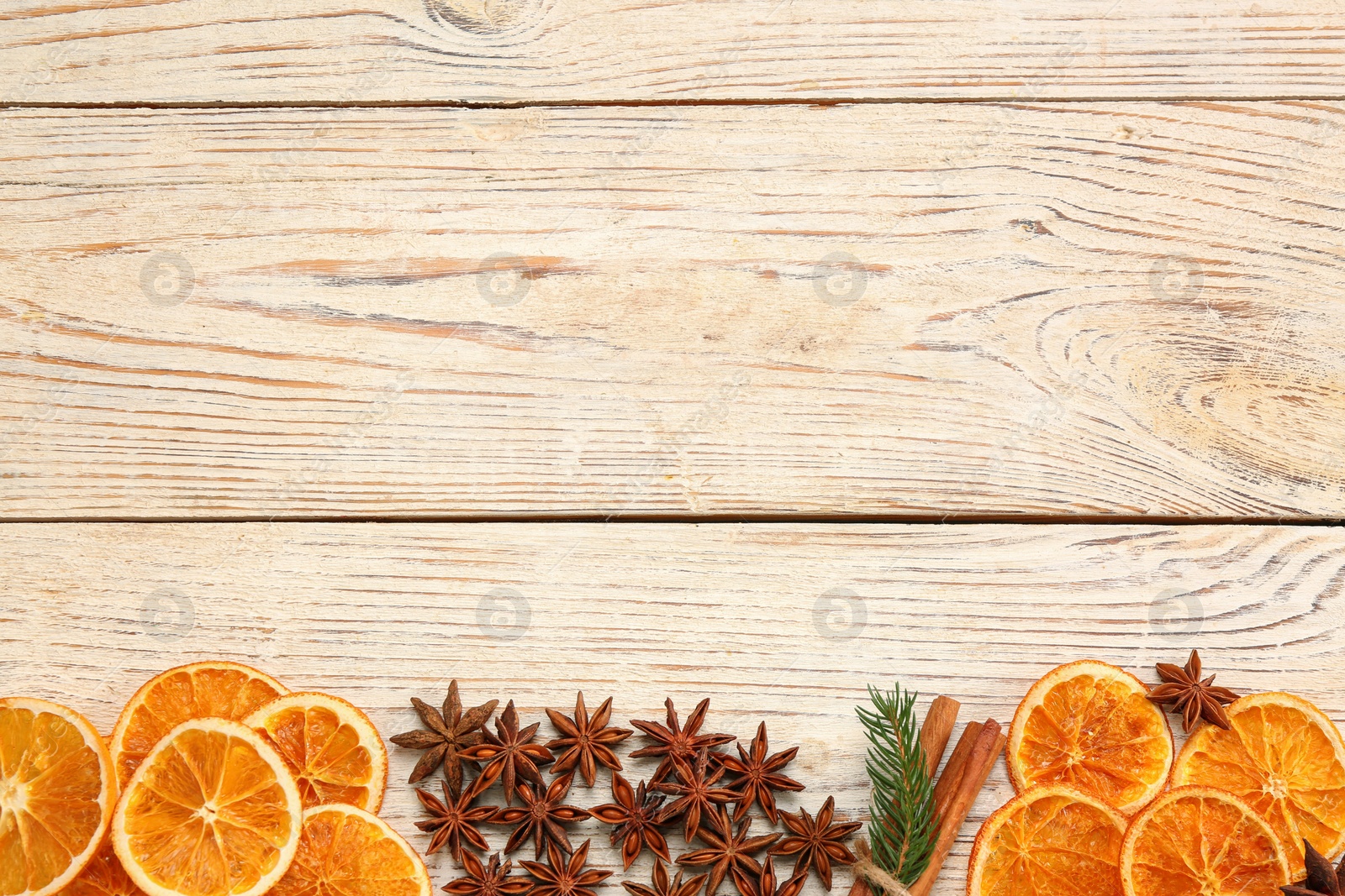 Photo of Dry orange slices, cinnamon sticks and anise stars on white wooden table, flat lay with space for text