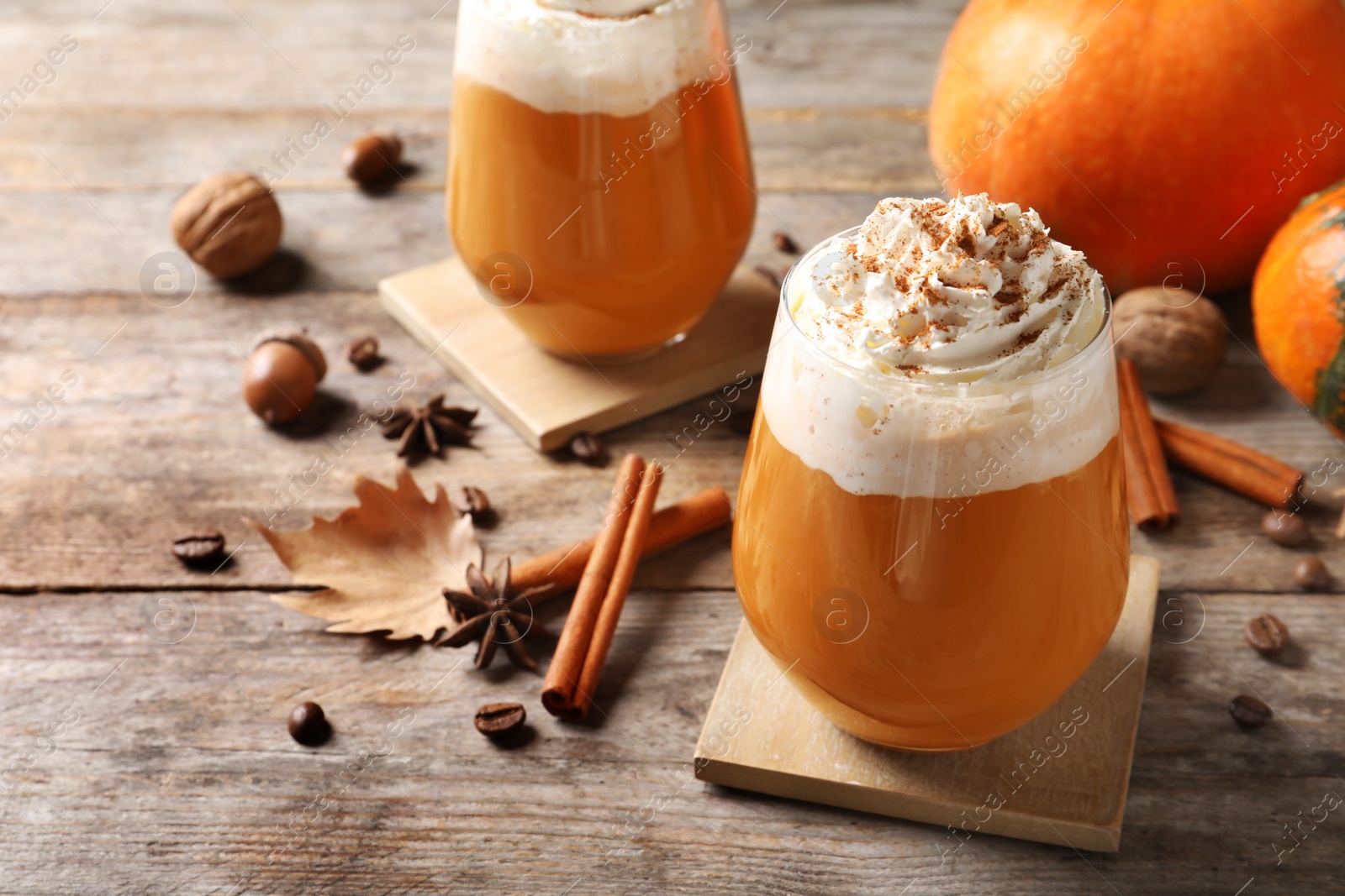 Photo of Glasses with tasty pumpkin spice latte on wooden table