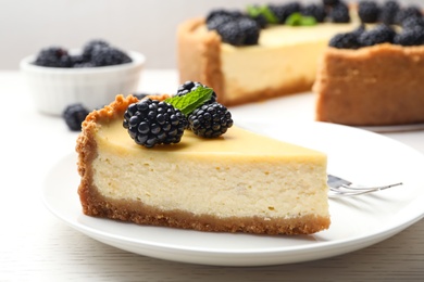 Photo of Piece of delicious cheesecake decorated with blackberries on table