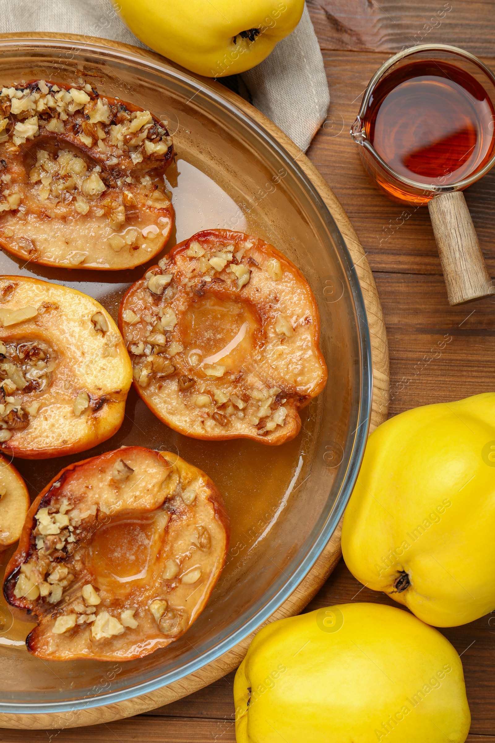 Photo of Tasty baked quinces with walnuts and honey in bowl on wooden table, flat lay