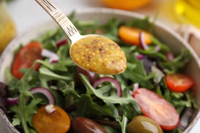 Photo of Spoon with tasty vinegar based sauce (Vinaigrette) over salad, closeup