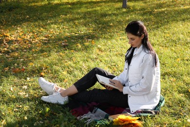 Photo of Happy woman reading book in park on autumn day