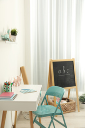Table with chair near white wall in child room