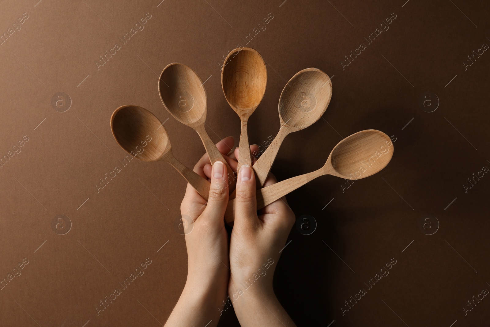 Photo of Woman holding empty wooden spoons on color background, closeup