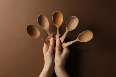 Photo of Woman holding empty wooden spoons on color background, closeup